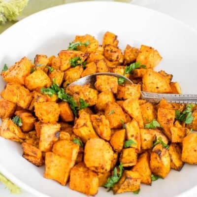 a spoon diffing into air fryer sweet potato cubes