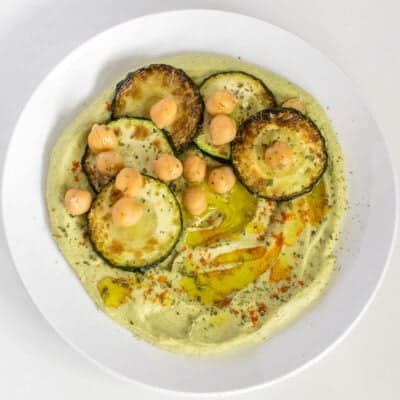 top view of served zucchini hummus with garnishes.