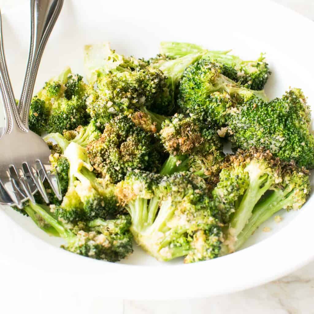 close up view of air fryer crispy broccoli served in a plate. 