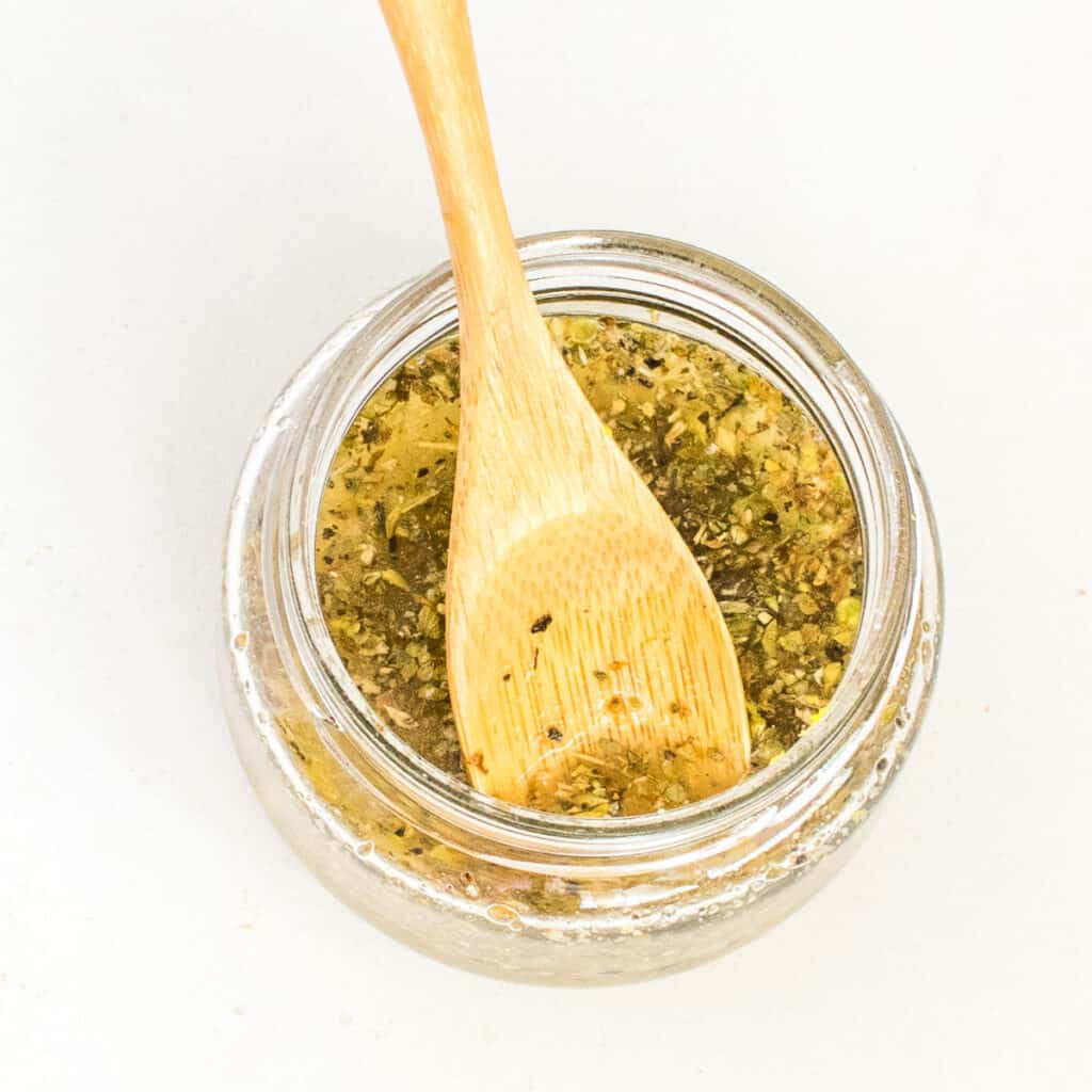salad dressing in a glass jar with a wooden spoon.