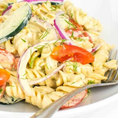 a close up view of tomato cucumber pasta salad.