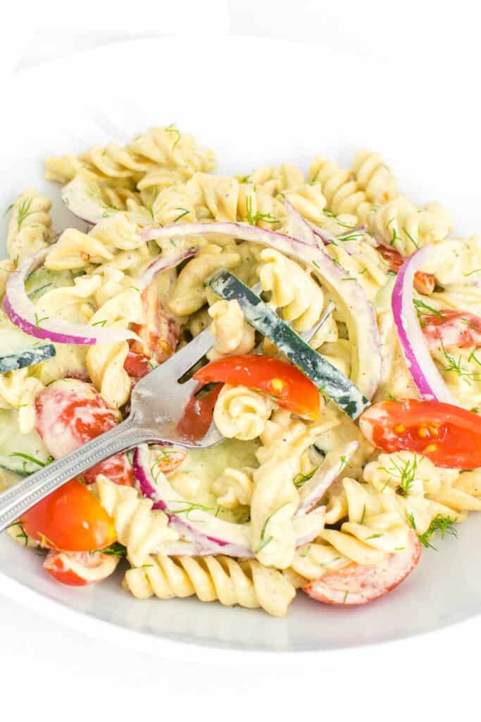 a fork full of the tomato cucumber pasta salad with a close up view. 