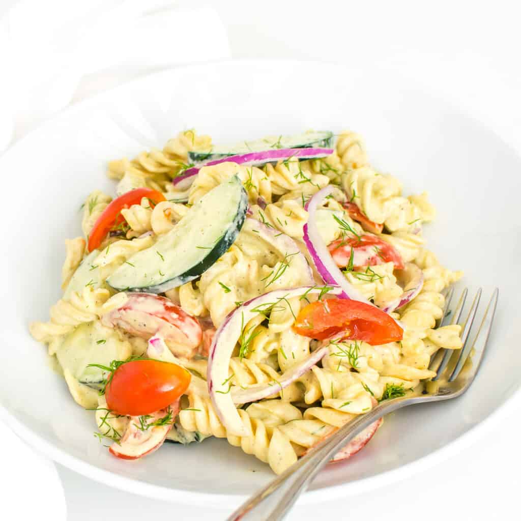 a 45 degree angle view of tomato cucumber pasta salad served in a plate.
