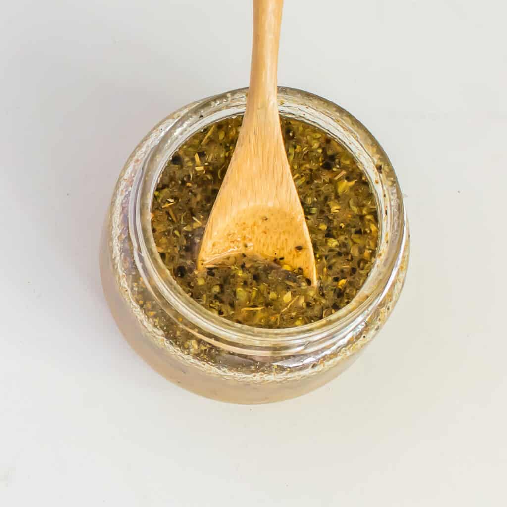 dressing in a glass jar with a wooden spoon.