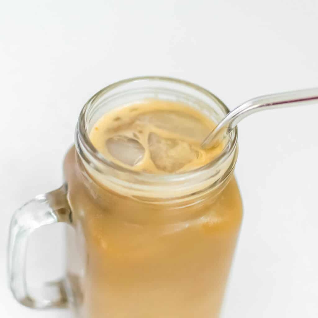 a 45 degree angle view of iced pumpkin latte in the serving glass without whipped cream as the garnishing. 
