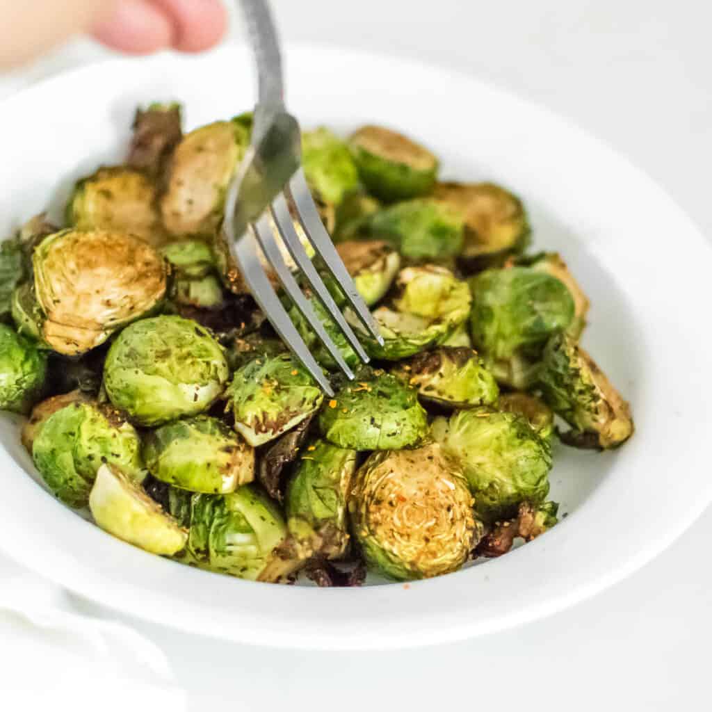 a fork digging into the served air fryer brussels sprouts. 