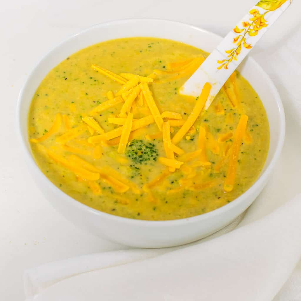 a close up view of a bowl full of vegan broccoli cheddar soup. 