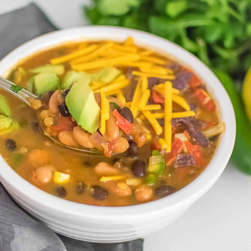 a spoon picking up a bite of vegan taco soup. 