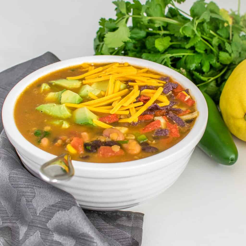 vegan taco soup ladled in a bowl with garnishes and a bunch of fresh cilantro at the backdrop. 