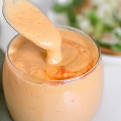 silken tofu salad dressing pouring from a spoon into the jar.