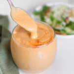 silken tofu salad dressing pouring from a spoon into the jar.