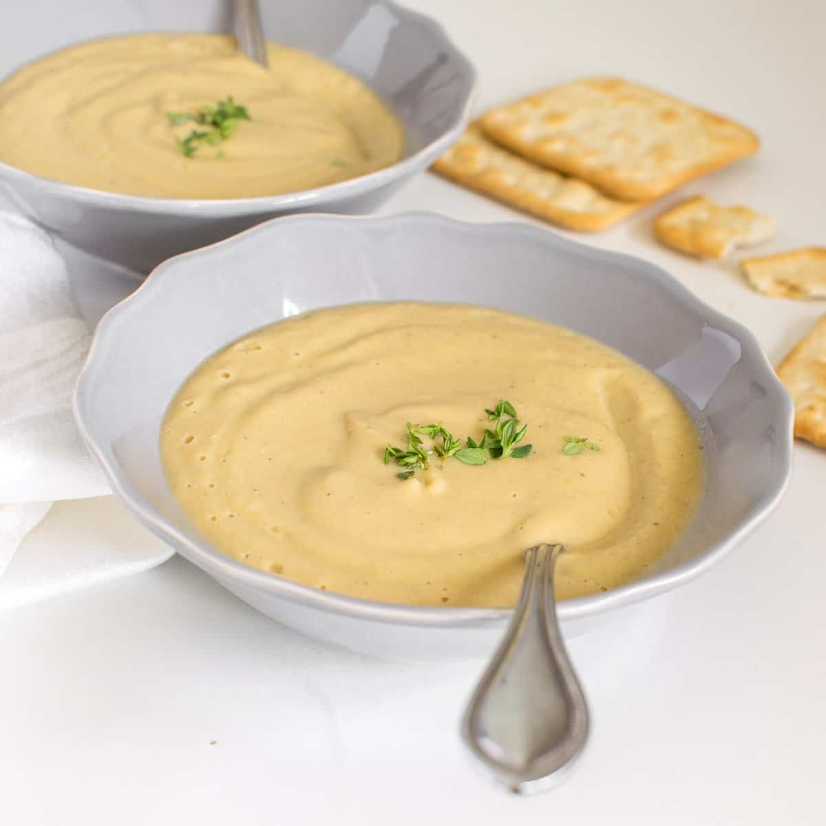 a front view of vegan cauliflower soup served with crackers.