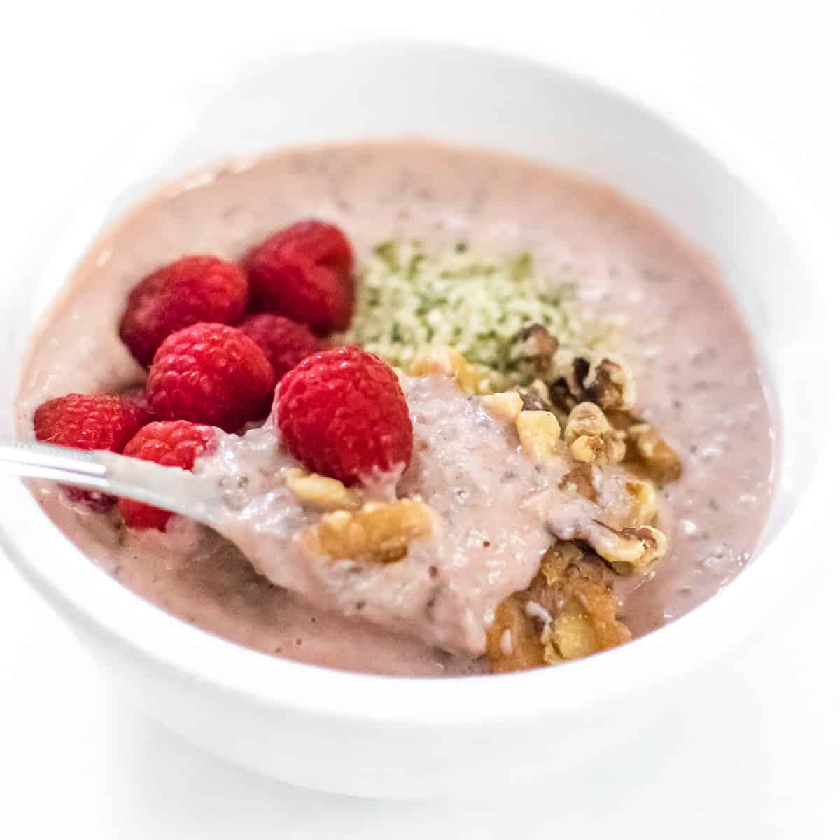 a spoon full of raspberry smoothie bowl in focus. 