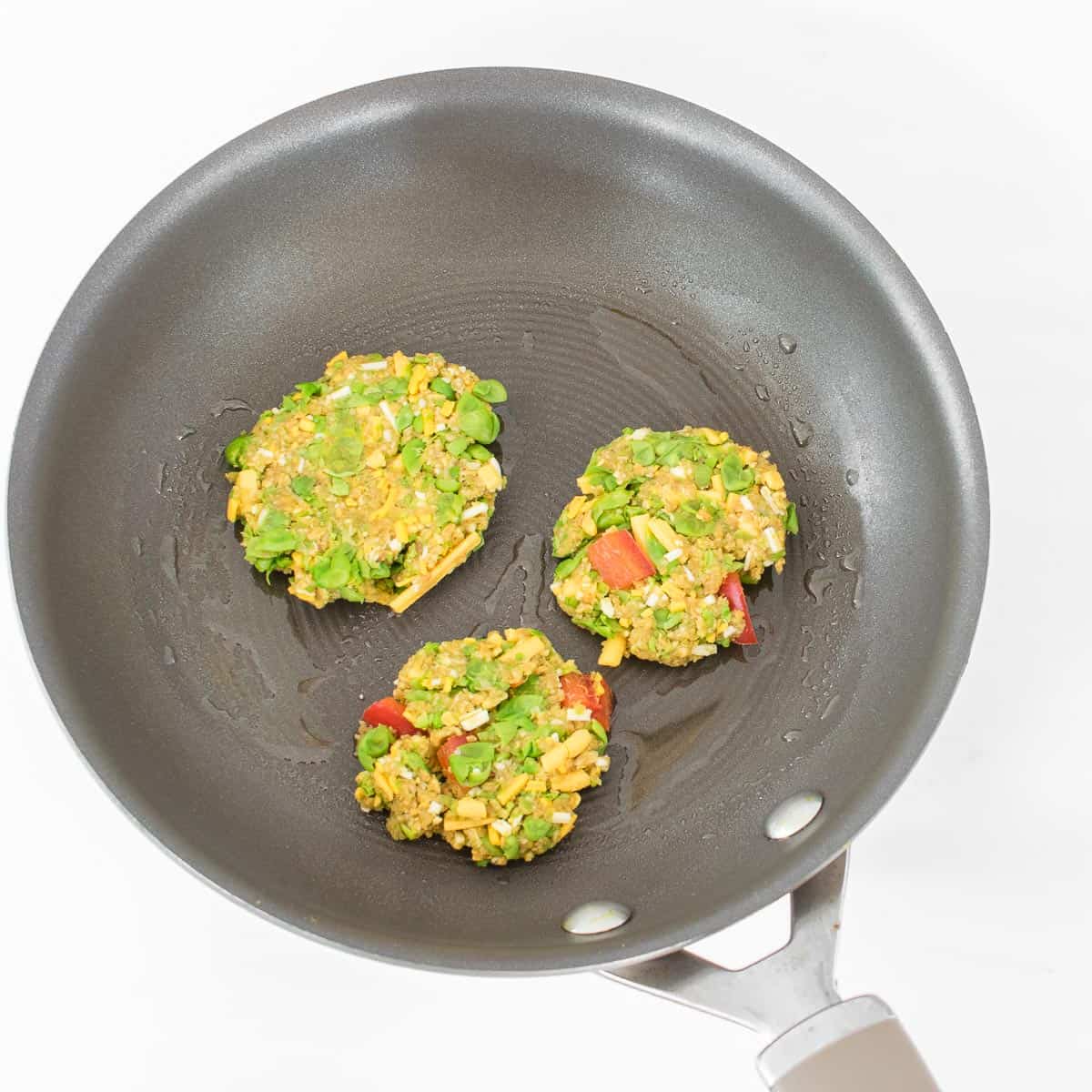 green pea fritters getting cooked in the pan. 