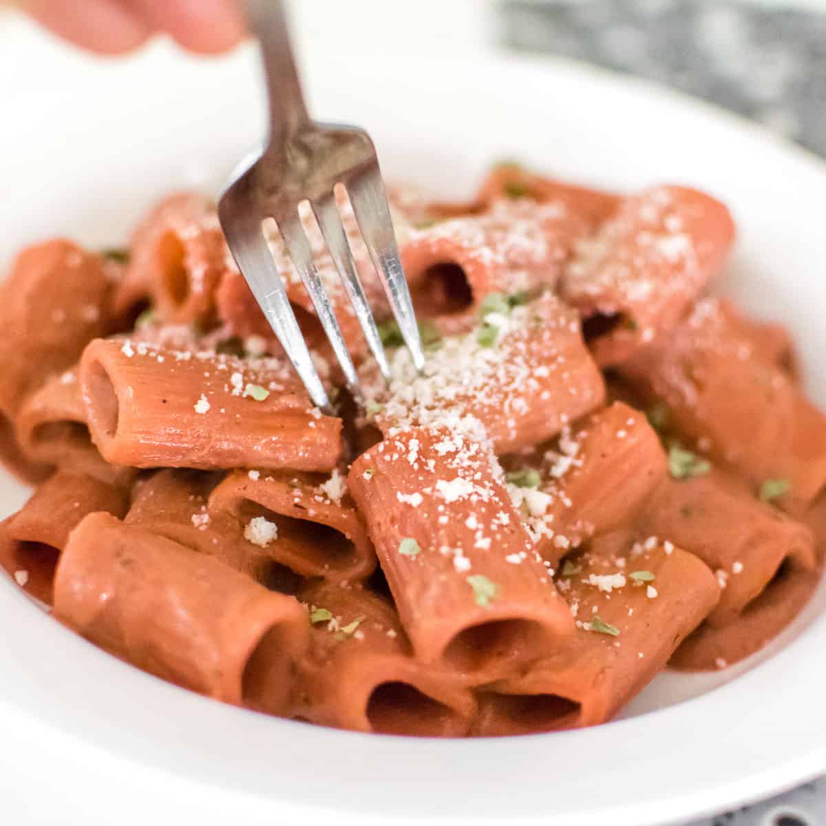 a fork digging into served beetroot pink sauce pasta. 