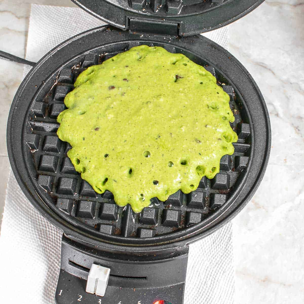 batter being cooked in the waffle maker.