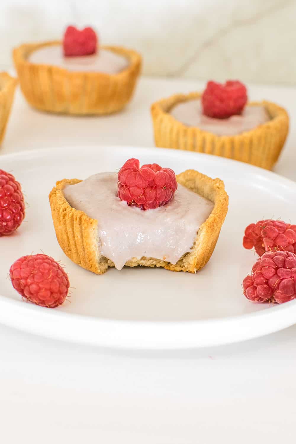 a close up view of one of the half eaten mini raspberry tarts. 