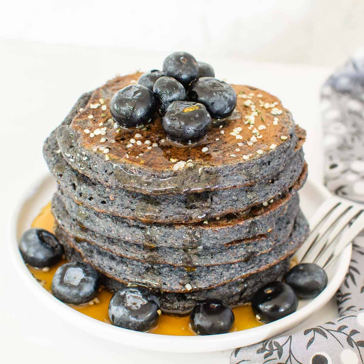 a 45 degree angle view of stacked vegan blueberry spelt flour pancakes. 