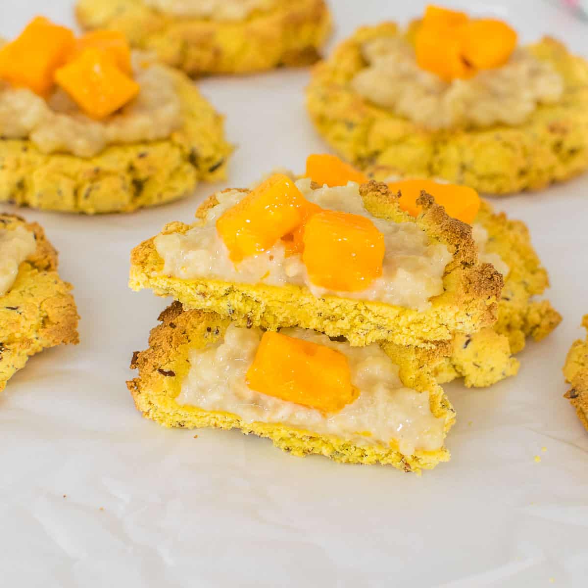 front view of broken pieces of mango coconut flour cookies stacked on each other. 