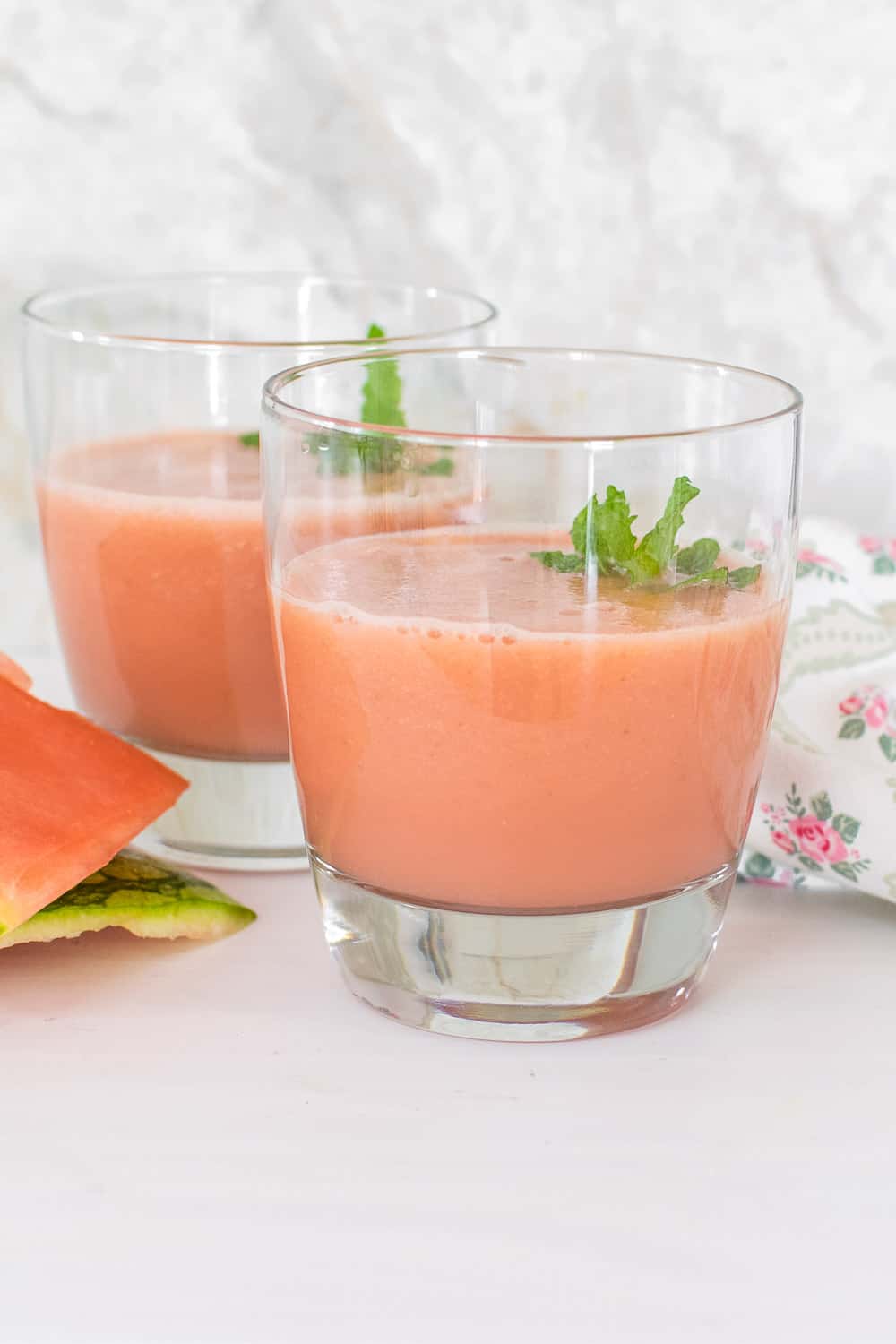 tall glasses filled with watermelon smoothie and garnished.