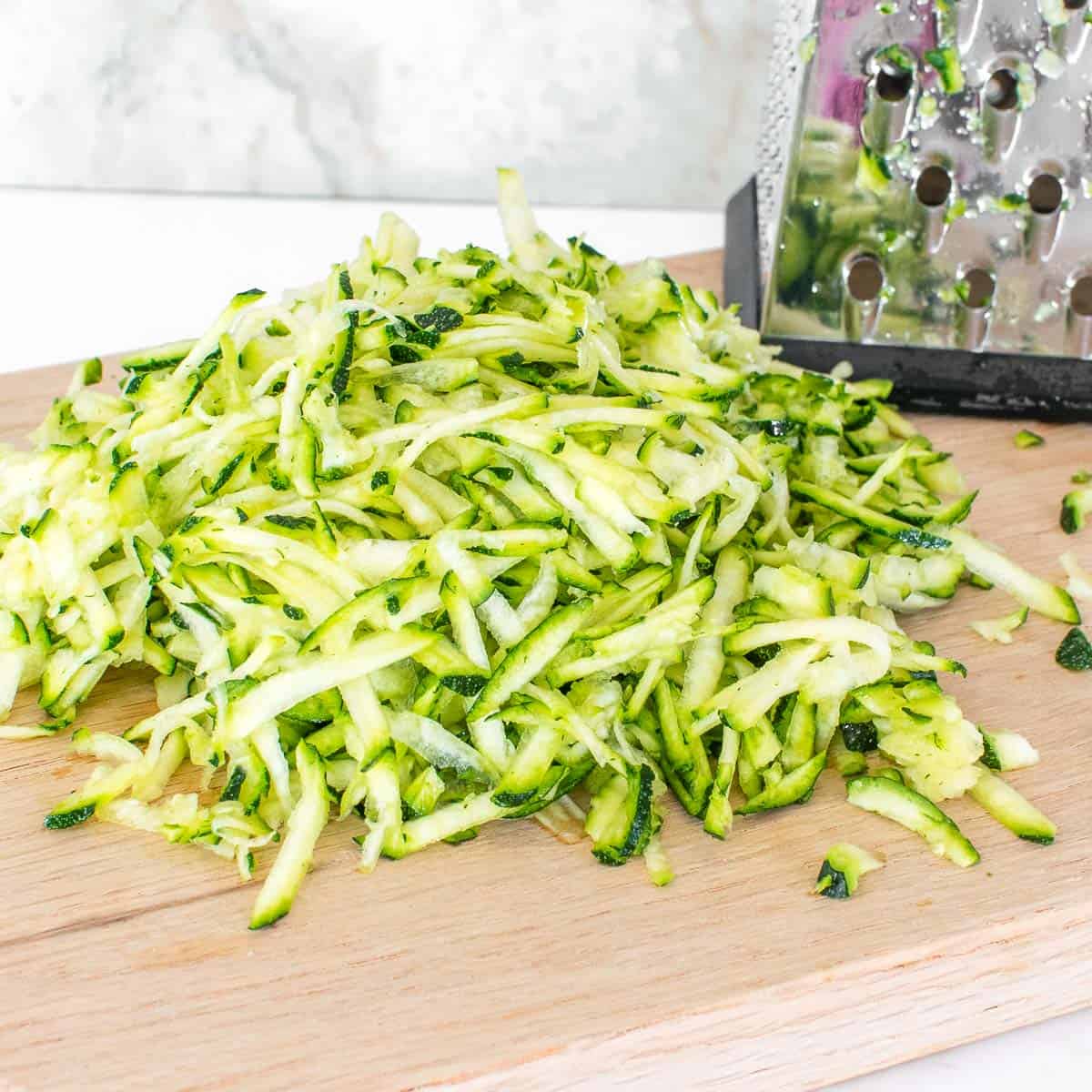 grated zucchini on a wooden cutting board.