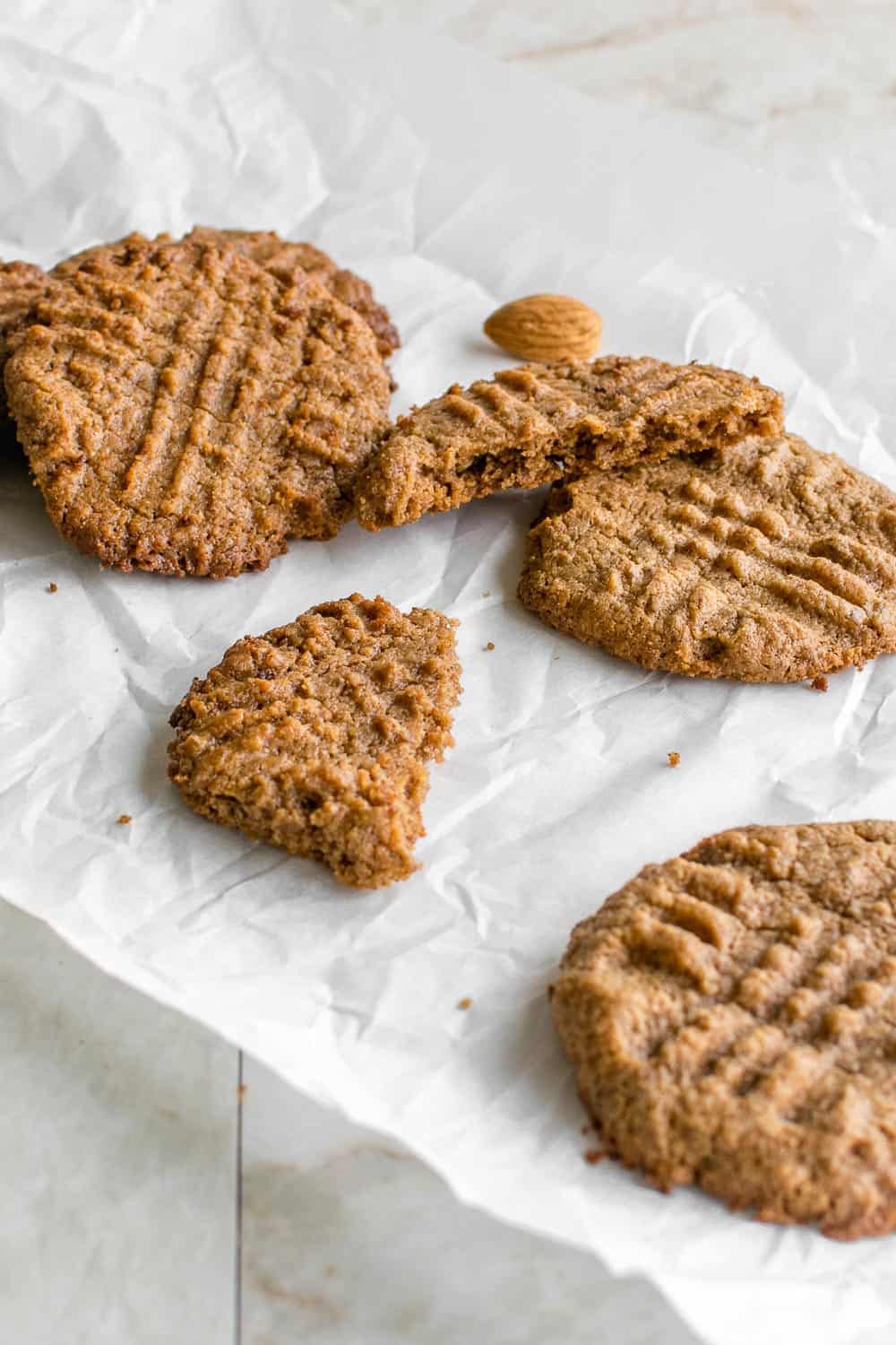 scattered vegan almond butter cookies on a parchment paper. 