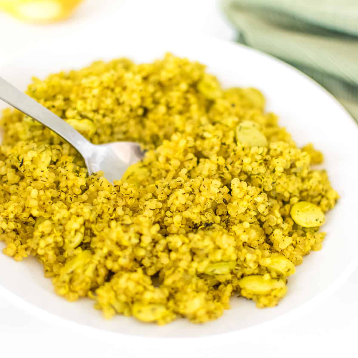 a spoon digging into lemon dill quinoa served in a plate.