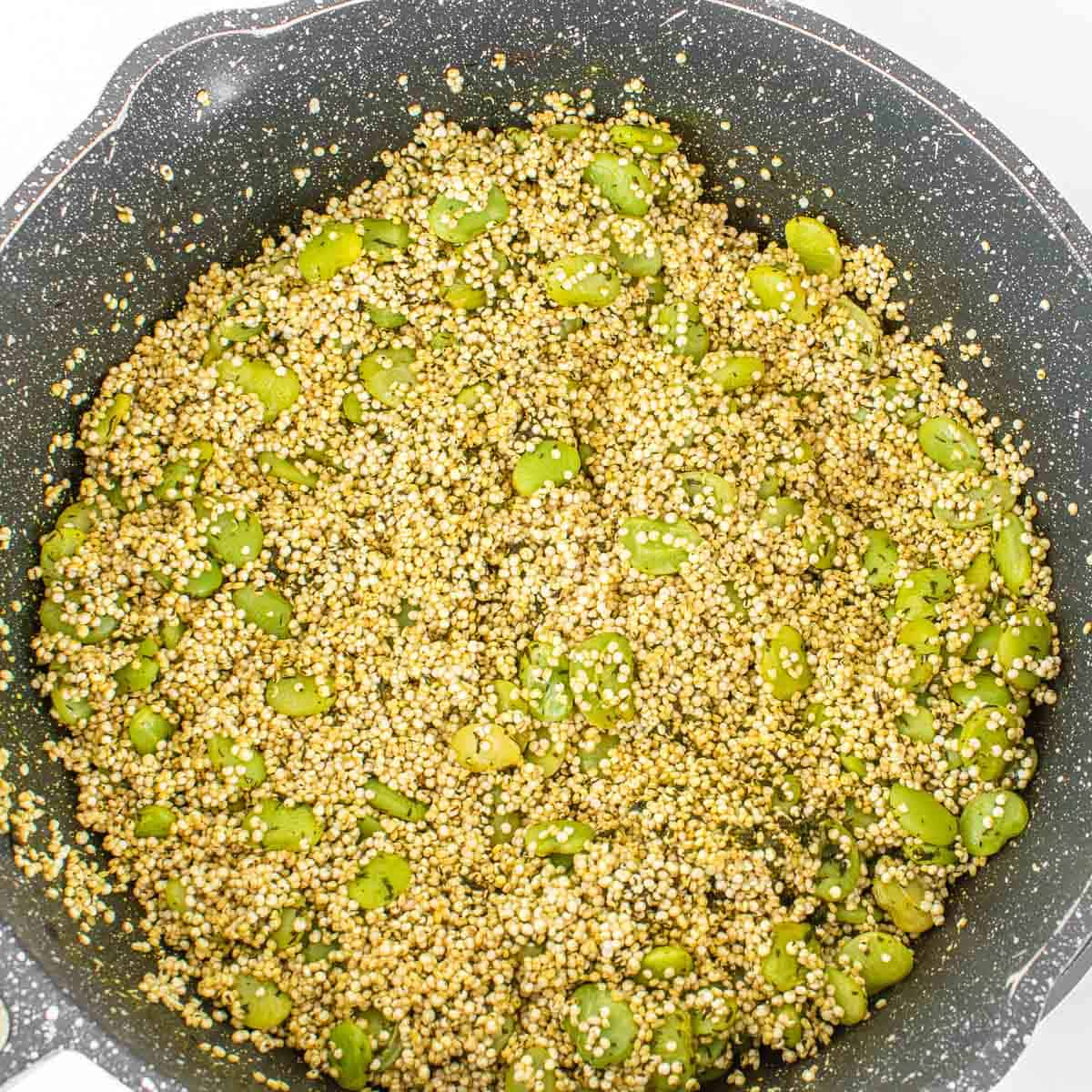 quinoa folded in with other ingredients in the pan. 