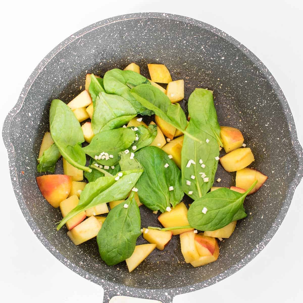 spinach tossed in with apples in the pan.
