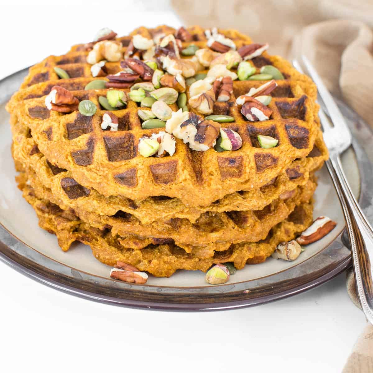 a 45 degree angle view of stacked whole pumpkin waffles.