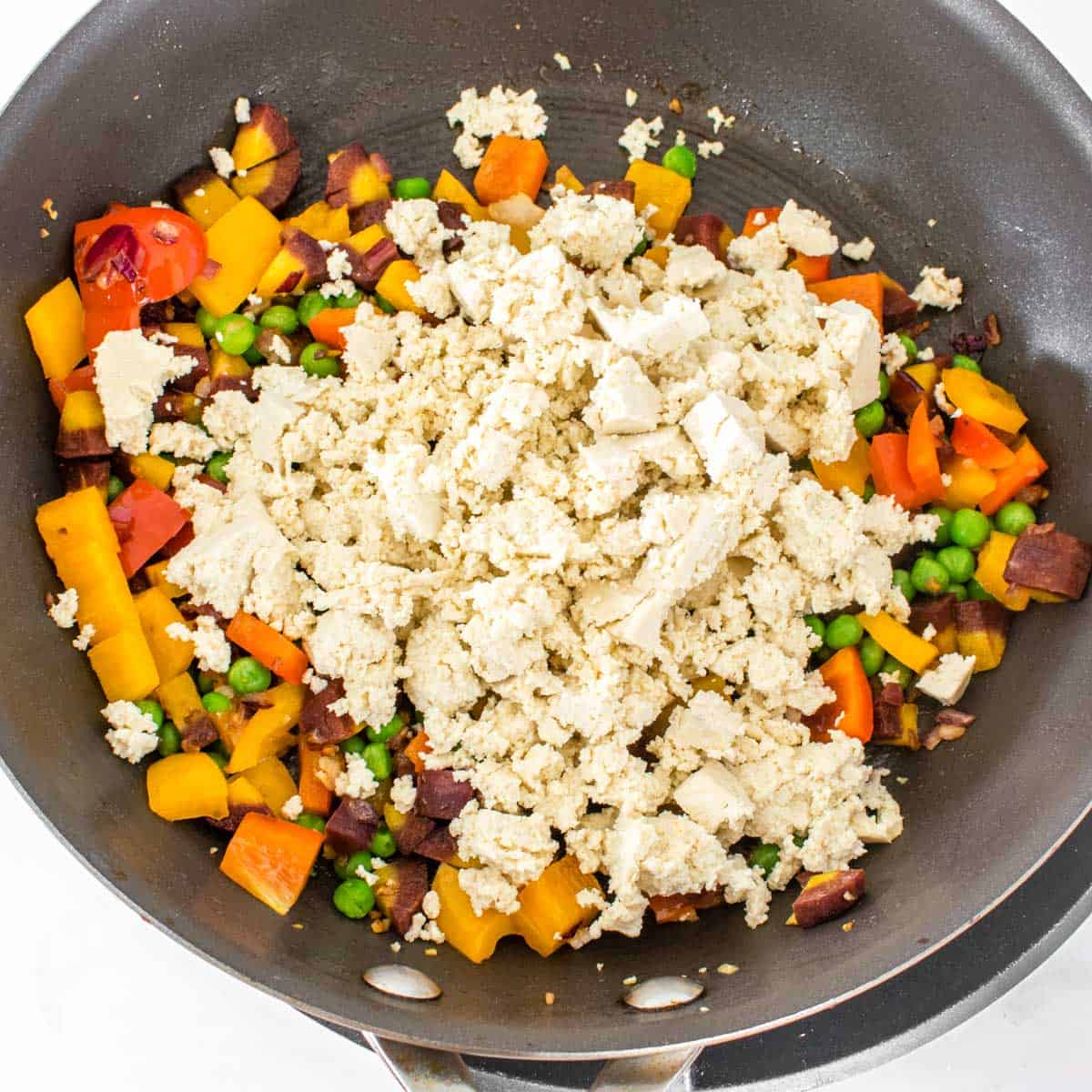 crumbled tofu tossed in with vegetables in the pan.