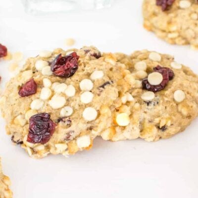 vegan white chocolate cookies on top of each other with cranberries scattered.