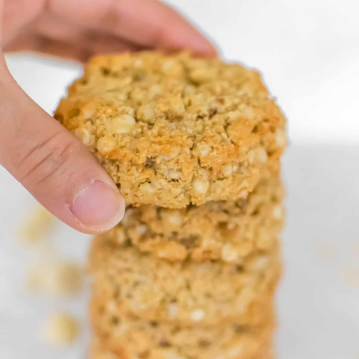 a hand placing a macadamia cookie on top of its stack. 