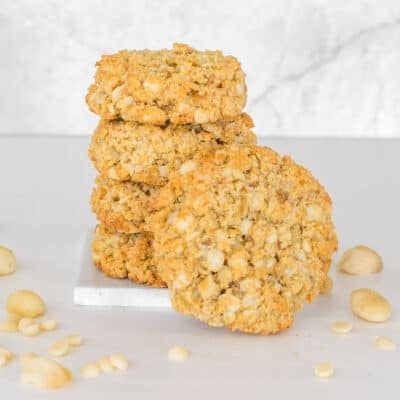 a cookie facing the front with the support of stacked vegan macadamia nut cookies.