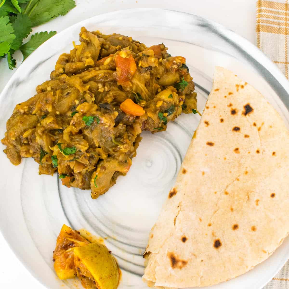 top view of the served plate with a serving of baingan bharta with roti and pickles.