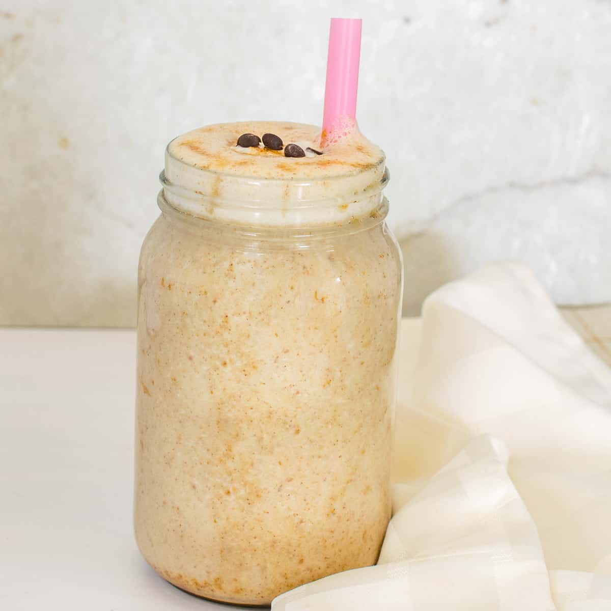 a front view of a tall glass filled with salted caramel protein shake and garnished.
