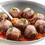 a spoon scooping the black bean meatballs from the cooking pan.