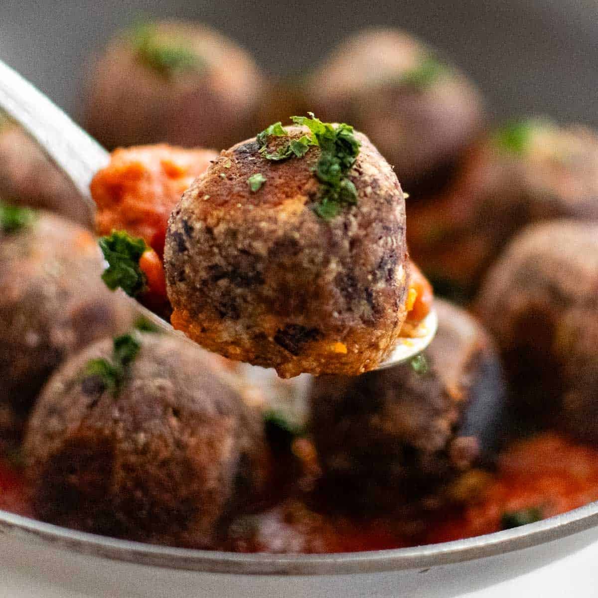 close up view of one of the black bean meatballs scooped in a spoon.