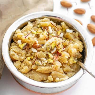 a 45 degree angle view of served badam halwa in an Indian bowl.