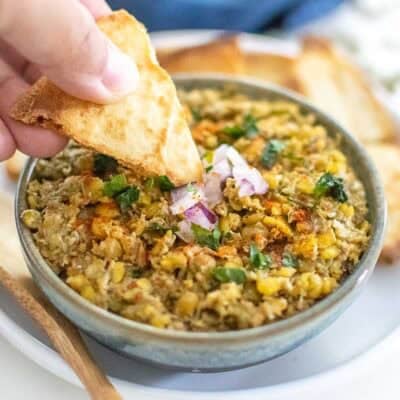 a hand dipping the chip in a bowl of lentil dip.