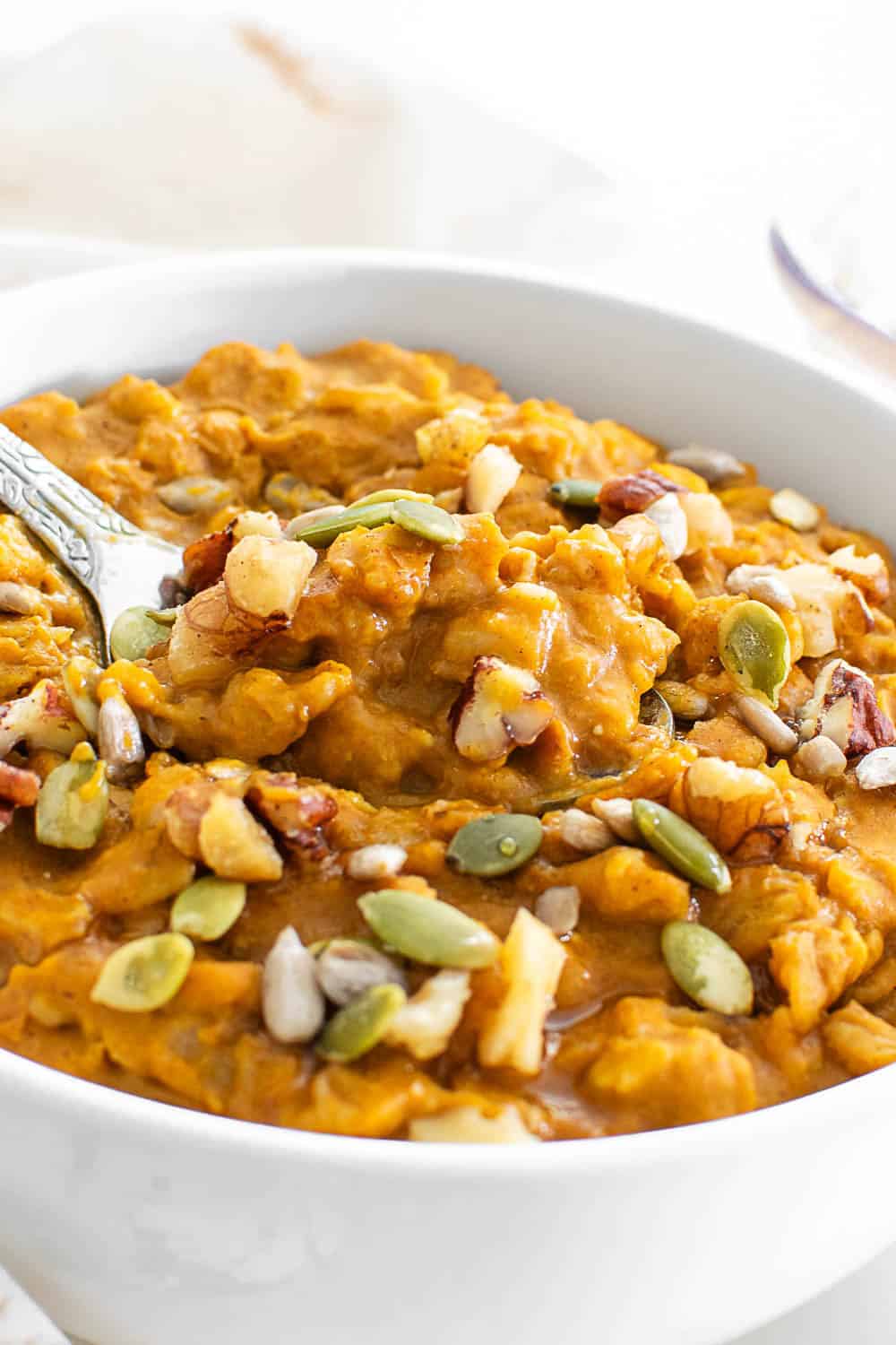a spoon with pumpkin oatmeal in the served bowl.