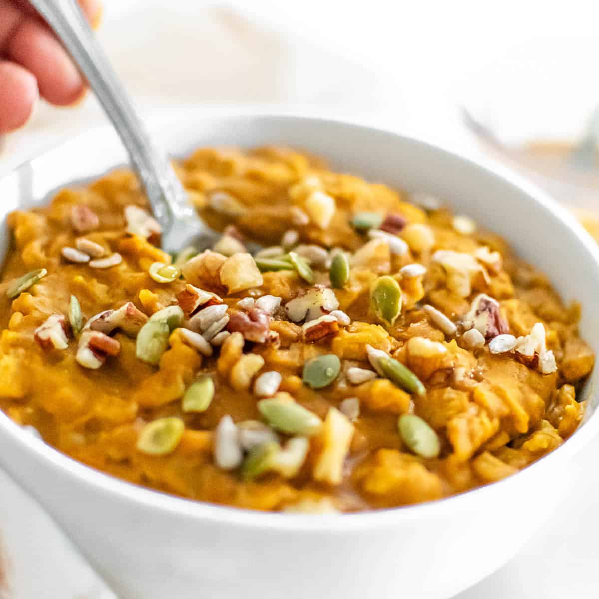 a spoon digging into the bowl of pumpkin oatmeal.