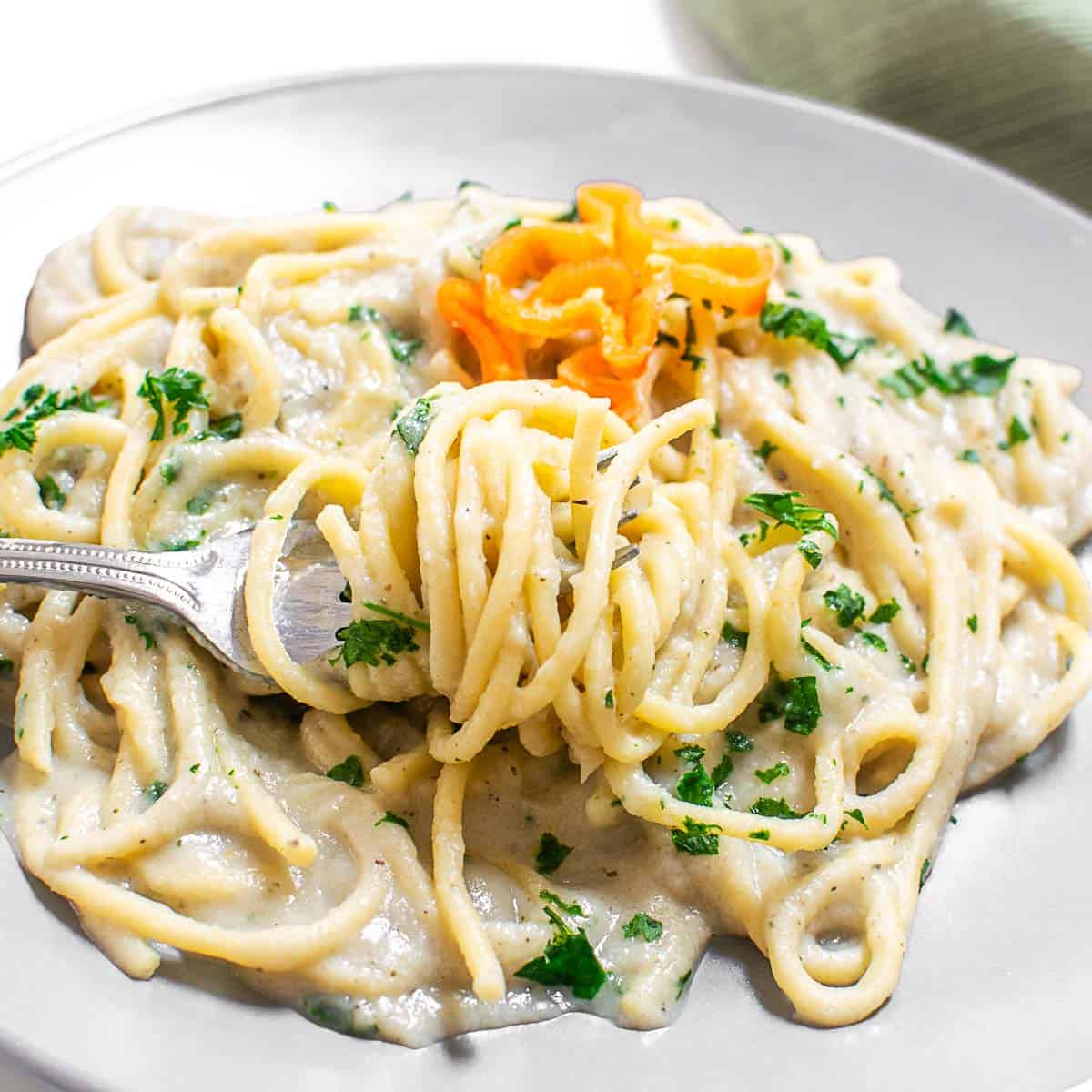 A 45 degree angle view of twirled cauliflower alfredo sauce spaghetti on the fork.