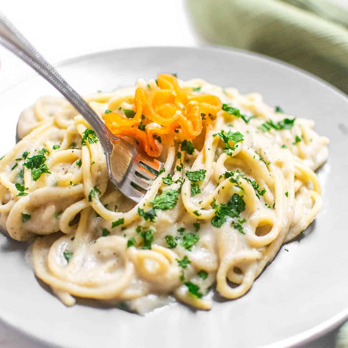 a fork digging into alfredo pasta.
