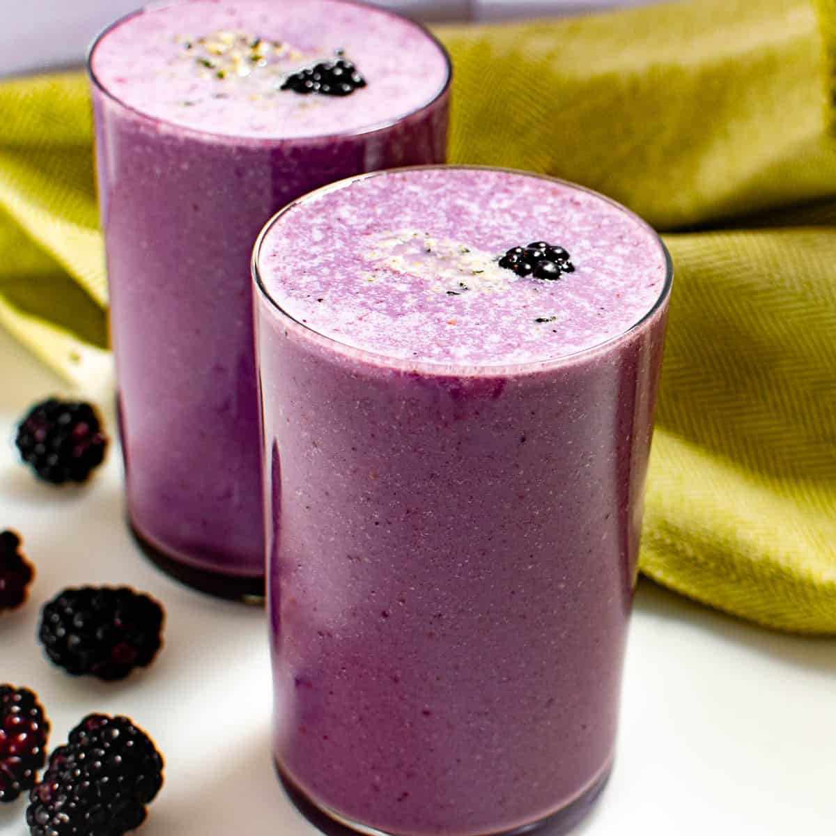 front view of blackberry smoothie served in glasses.