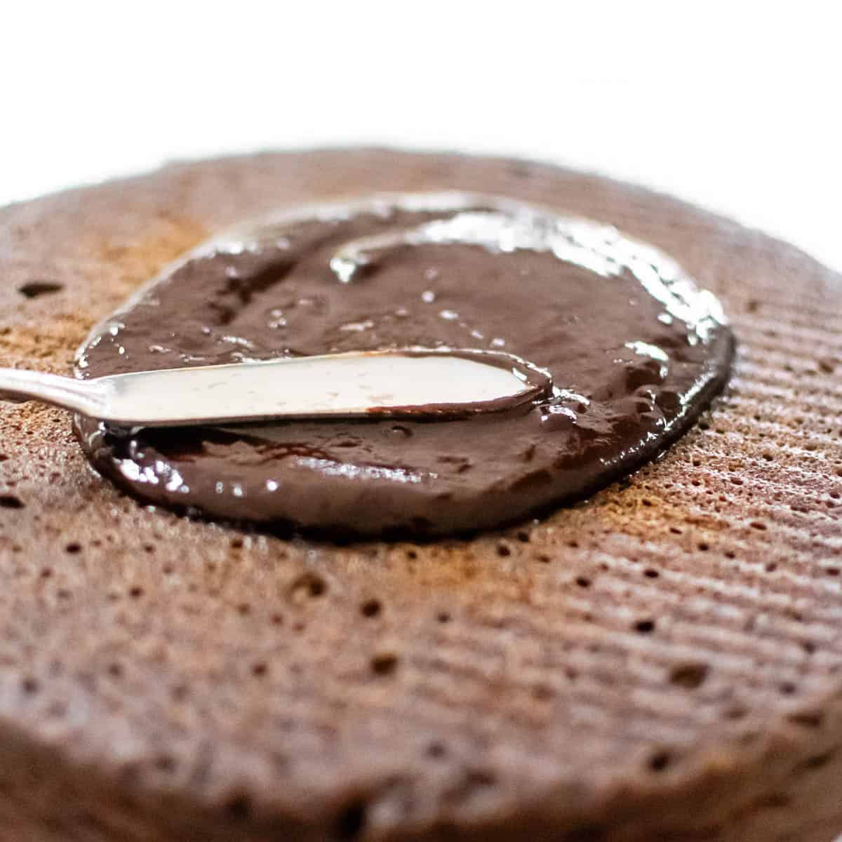 frosting being smeared over the cake with a butter knife.