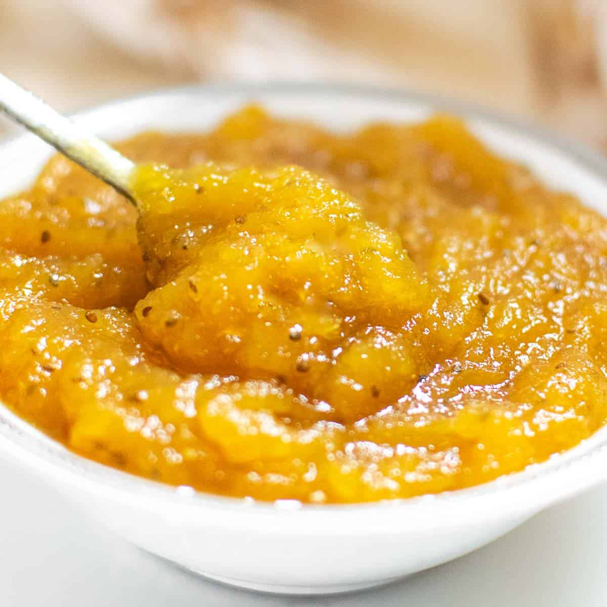 a spoon digging into a bowl of pineapple jam.