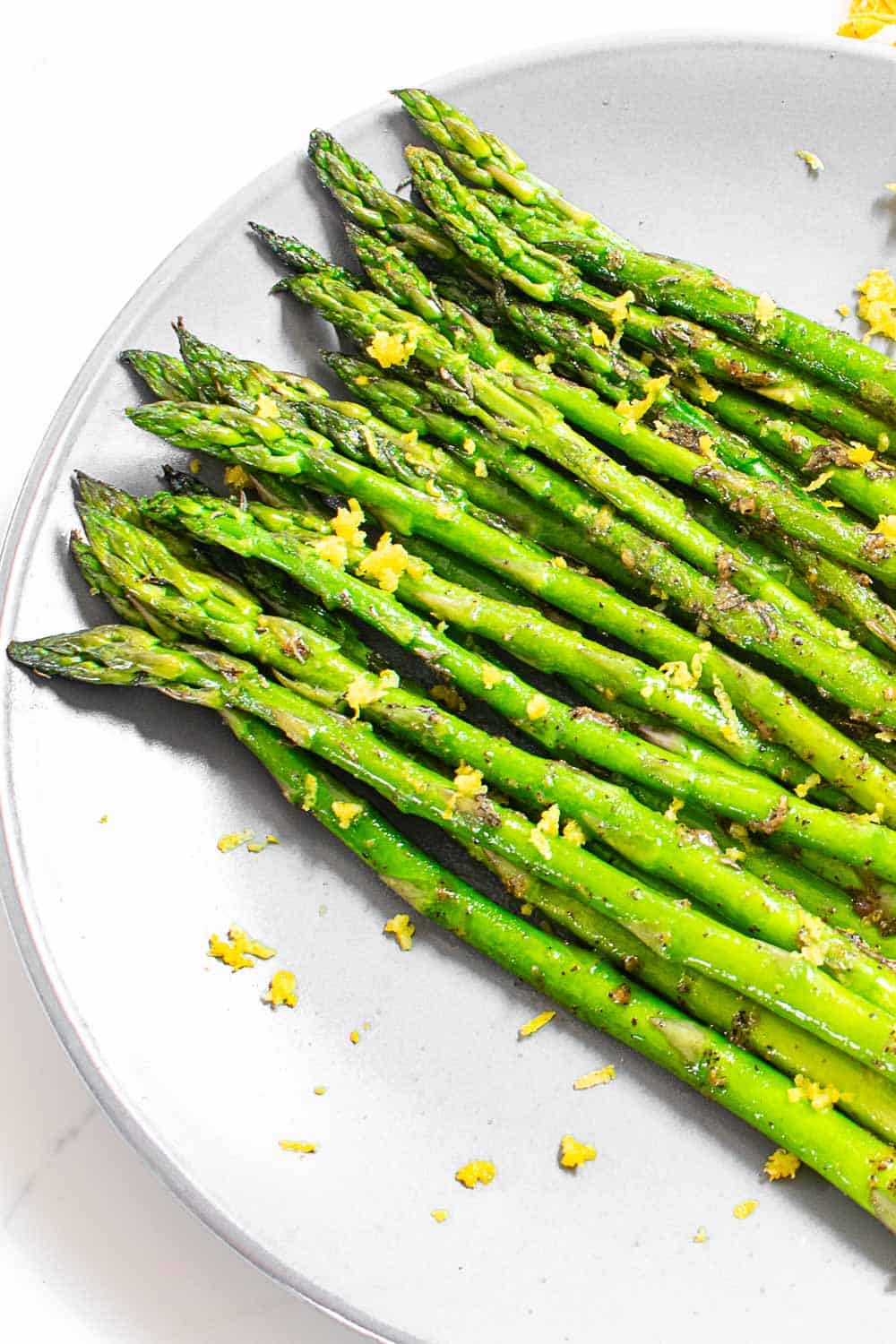 top angle view of pan fried asparagus served on a plate and garnished. 