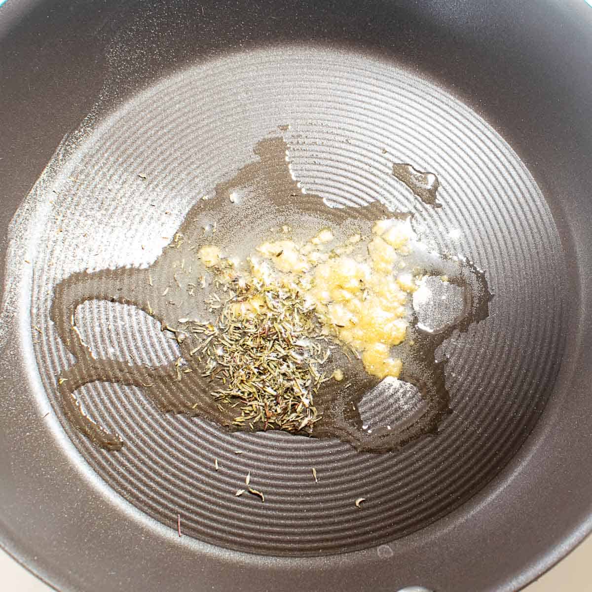 herbs and oil heated in a pan.