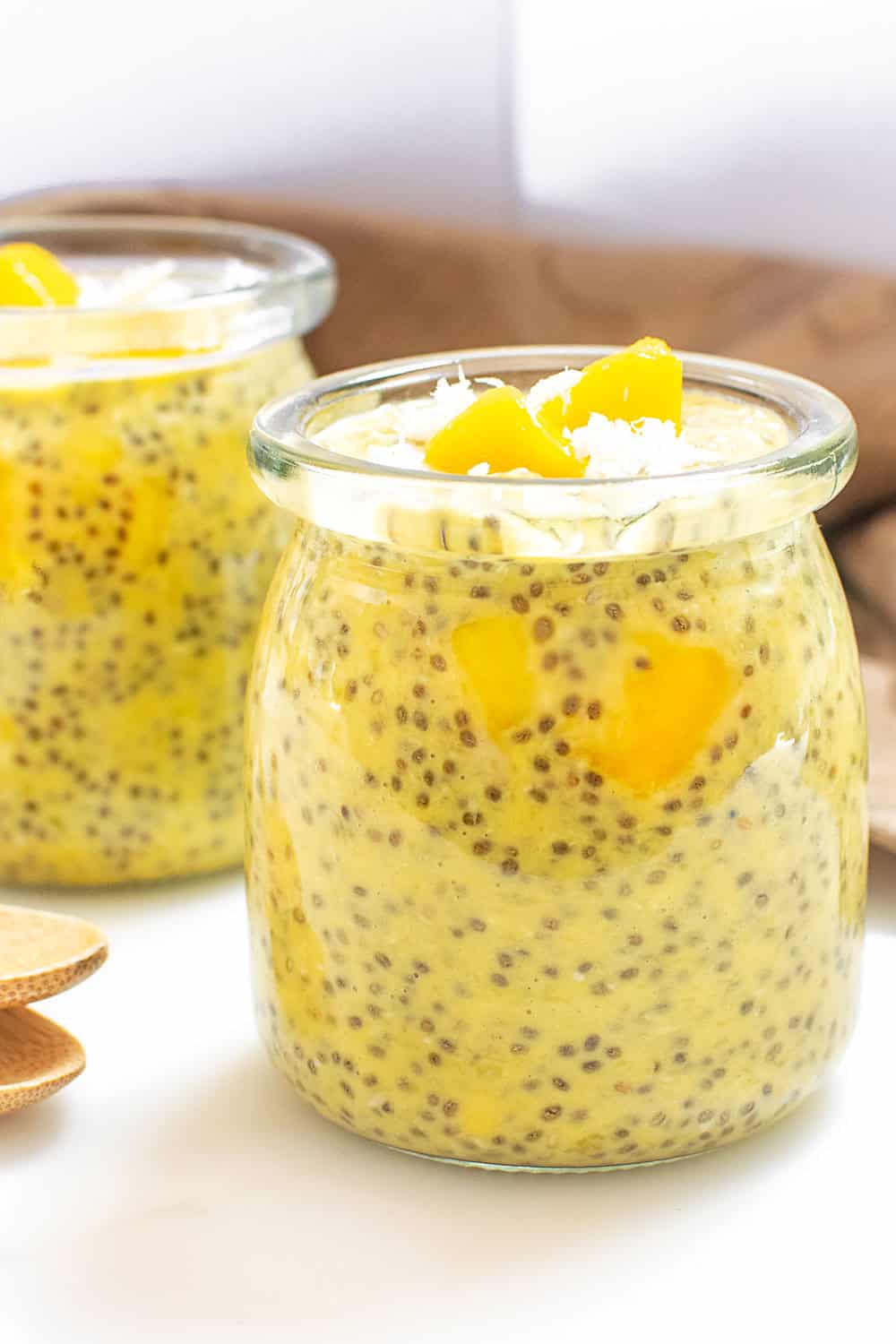 a front view of served mango chia pudding in glass jars.